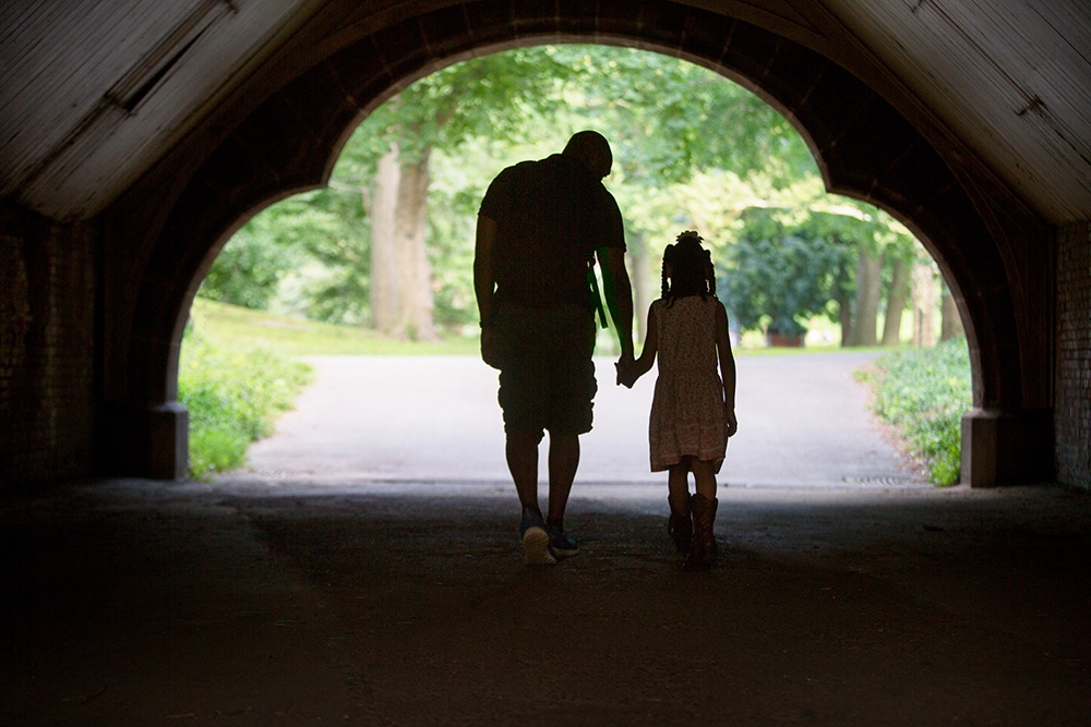 Father and Daughter walking through a tunnel, in silhouette